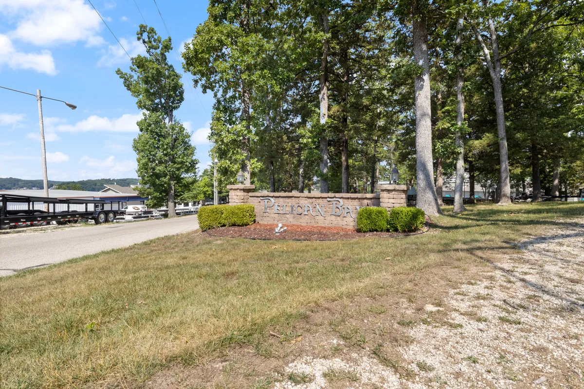 The entry sign for Pelican Bay stands amidst mature trees and a grassy area, creating a warm and inviting first impression. The image hints at the welcoming, nature-focused spirit of the community and its easy access to the outdoors.
