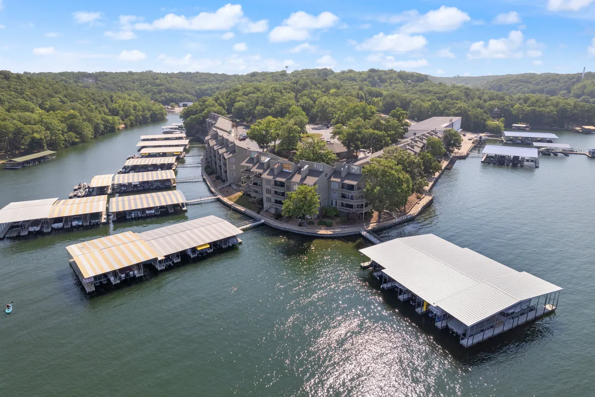 A relaxed waterfront view showcasing a marina with boat docks, waterfront buildings, and lush greenery. The scene captures a tranquil moment by the lake, with the docks ready for fishing, boating, and evening strolls.