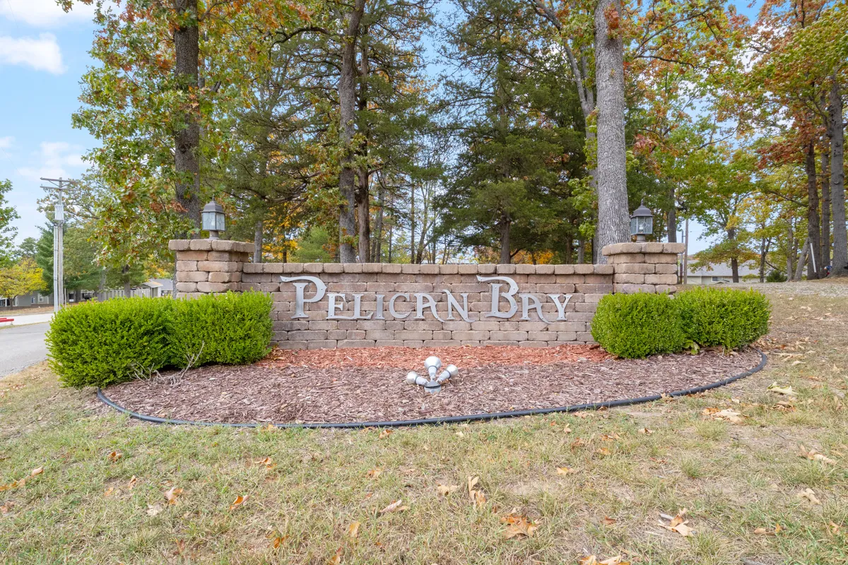 The welcoming entrance to Pelican Bay, featuring a prominent sign, landscaped greenery, and mature trees. The pathway and open space evoke a sense of community and provide a first impression of the neighborhood's inviting atmosphere.